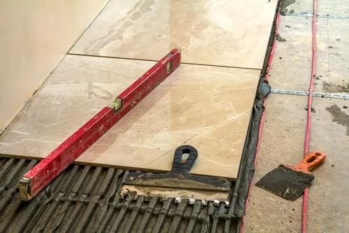 Large-format tile flooring installation set level with spacers and a tile leveling tool