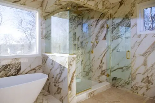 Custom tiled walk-in shower with glass panel next to a tiled tub surround